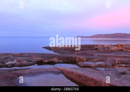 Winter sunset with atmospheric colours at the rocky shores of Trondheimsfjorden, Flatholmen, Norway. Stock Photo