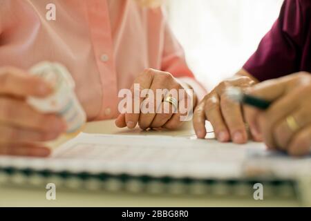 Hands of a nurse and a senior patient holding a bottle of pills Stock Photo