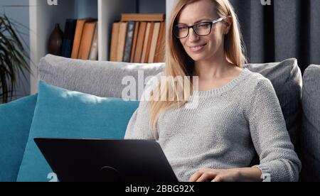 Woman using laptop on couch Stock Photo