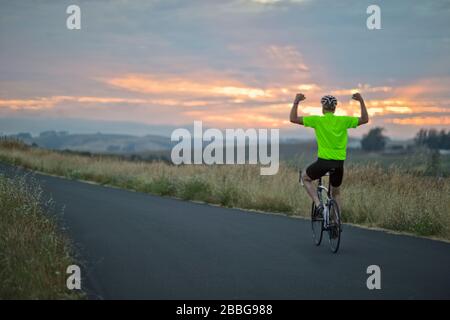 Mature man showing off while riding a bike along a country road Stock Photo