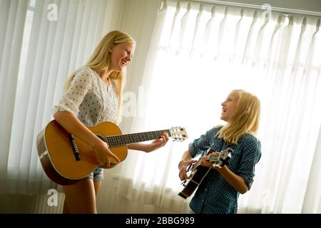 Happy teenage girls playing guitar and mandolin together Stock Photo