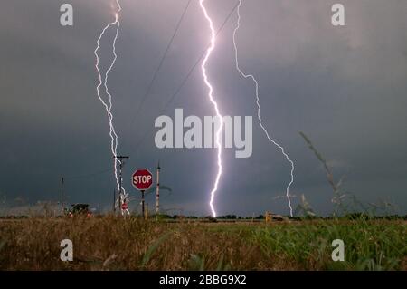 Storm with lightning strikes over a rural field in Oklahoma United States 4 image merge incliuding a lightning strike hitting a power pole. Stock Photo