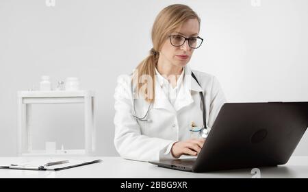 Focused female doctor using laptop Stock Photo