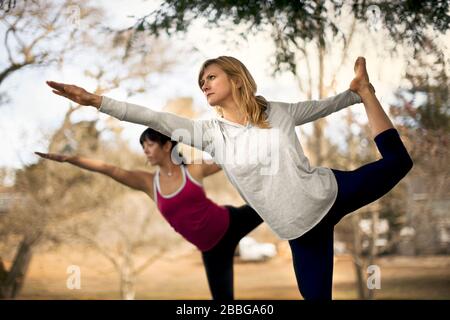 Two women practicing yoga poses in the park Stock Photo