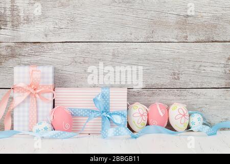 Easter greeting card with colorful easter eggs and gift boxes in front of wooden wall. With space for your greetings Stock Photo