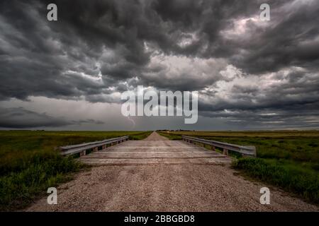 Storm with lightning flashing over old rural bridge on gravel road in rural southern Manitoba Canada Stock Photo