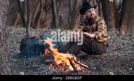 Outdoorsman warming hands from campfire Stock Photo