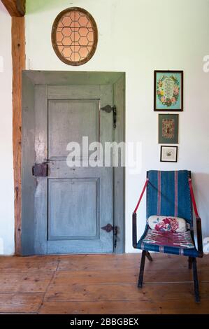 old grey painted door with wooden tramen, wooden floorboard and blue folding chair Stock Photo