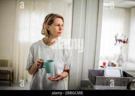 Mature woman drinking coffee in the kitchen Stock Photo