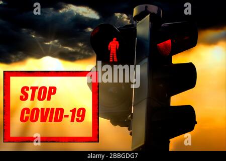 Stop Covid-19 concept with illuminated red traffic lights and dark sky background with sunrays. Stock Photo