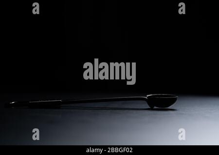 A black measuring spoon on black background. Stock Photo