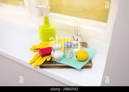 Natural cleaners concept. Natural organic eco friendly home cleaning ingredients, white vinegar, lemon, baking soda, citric acid on wood tray on windo Stock Photo