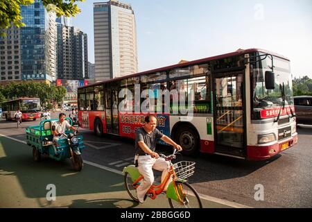 Commuters on bus bicycle and moped in traffic on street in Xian X'ian China Stock Photo