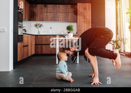 Father standing on his fingers next to his infant baby Stock Photo