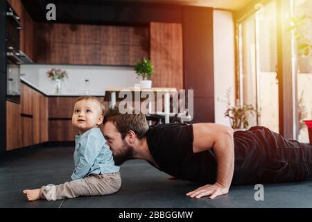 Happy father doing push upps next to his infant baby. Kissing his baby Stock Photo