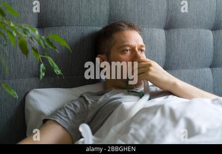 Sick man with inhalator mask on the face in bed. Coronavirus prevention concept. Stock Photo