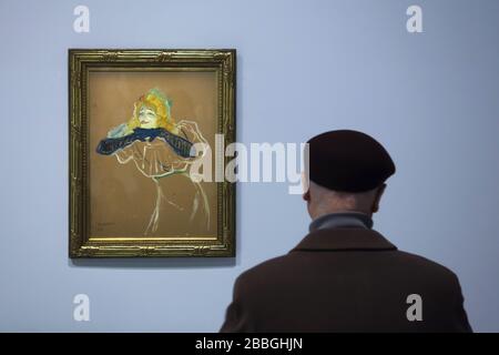 Visitor in front of the painting 'Yvette Guilbert sings Linger Longer Loo' by French Post-Impressionist artist Henri de Toulouse-Lautrec (1894) displayed at his retrospective exhibition in the Grand Palais in Paris, France. The first French retrospective exhibition of the artist in last 28 years runs till 27 January 2020. Stock Photo