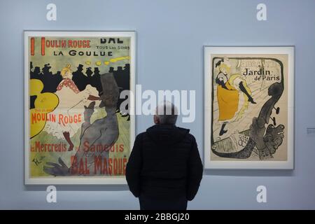 Visitor in front of the posters by French Post-Impressionist artist Henri de Toulouse-Lautrec displayed at his retrospective exhibition in the Grand Palais in Paris, France. The famous posters 'Moulin Rouge. La Goulue' (1891) and 'Jane Avril. Jardin de Paris' (1893) is pictured from left to right. Famous French cancan dancers La Goulue (Louise Weber), Valentin le Désossé (Jacques Renaudin) and Jane Avril are depicted in the posters. The first French retrospective exhibition of the artist in last 28 years runs till 27 January 2020. Stock Photo