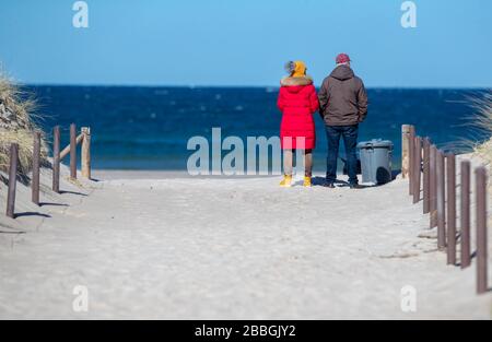 31 March 2020, Mecklenburg-Western Pomerania, Rostock-Warnemünde: Two walkers are standing on a beach access and look out over the Baltic Sea. Public life in Mecklenburg-Western Pomerania will be further restricted in connection with the protective measures against the spread of the coronavirus. Photo: Jens Büttner/dpa-Zentralbild/dpa Stock Photo