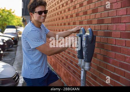 Magog, Quebec, Canada - September 8, 2018: Happy and joyful young man, guy smiles and pays for parking. Travel in Canada Stock Photo