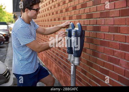 Magog, Quebec, Canada - September 8, 2018: Happy and joyful young man, guy smiles and pays for parking. Travel in Canada Stock Photo