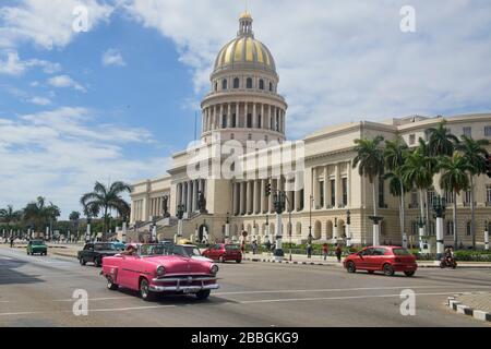 Classic cars drive past the Capitolio building, Havana, Cuba Stock Photo