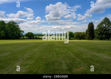 A wide angle photo looking over the beautiful rolling green hills of Montpelier, VA under a blue sky with dramatic clouds. Stock Photo