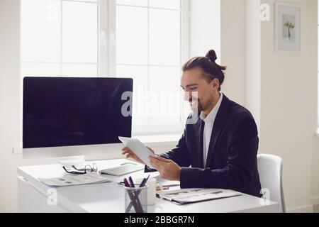 A businessman in a black jacket works analyzes the strategy at the computer at the workplace in the office. Stock Photo