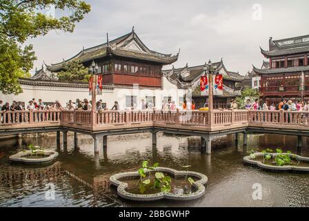 Shanghai, China - May 4, 2010: Yu garden off Yuyuan shopping streets. Pedestrian bridge over pond with buildings of traditional Chinese architecture i Stock Photo