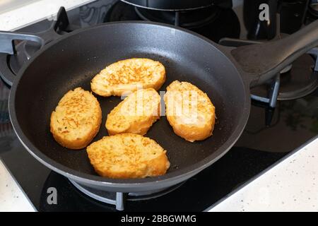 Bread croutons in an egg are fried in a pan. Close-up. Top-side view Stock Photo