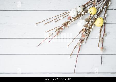 Easter decorations. Willow twigs and decorative Eggs on white wooden background. Stock Photo