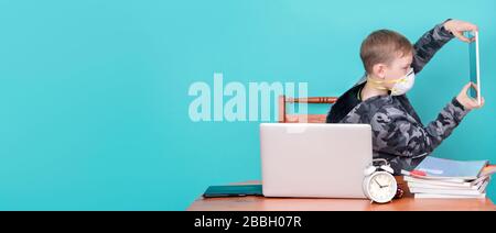 Kid wearing mask and doing homework at home. Home school concept. Stock Photo