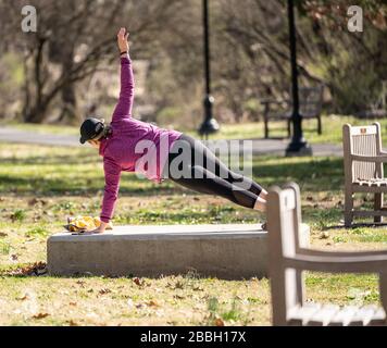 Berks County, Pennsylvania, USA-March 22, 2020: Fit young woman doing side planks  outdoors in public park. Stock Photo