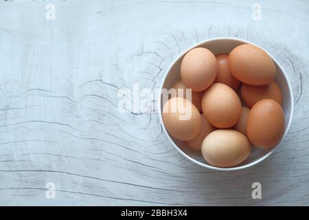 eggs in a wooden bowl on old wooden table top view. Stock Photo
