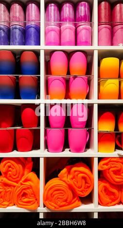 Colored gradient glasses on the shelves in the store. Cups of all colors of the rainbow on the counter of the store.Colorful mugs on shelf in retailer Stock Photo