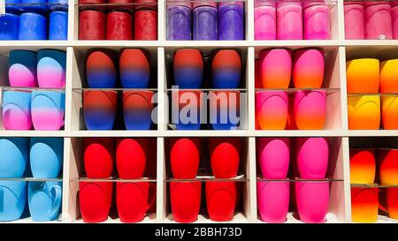 Colored gradient glasses on the shelves in the store. Cups of all colors of the rainbow on the counter of the store.Colorful mugs on shelf in retailer Stock Photo
