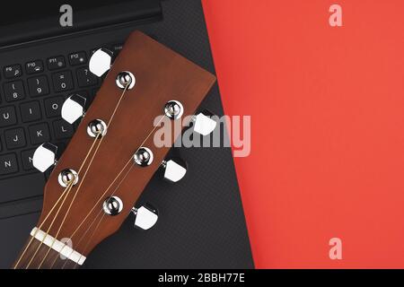 Online guitar learning concept with laptop and guitar on red backgrond. Minimal flat lay view Stock Photo