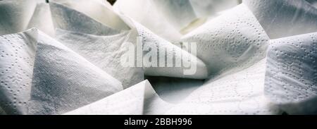 Close-up at folded unrolled white toilet paper. Banner proportioned high resolution image. Stock Photo