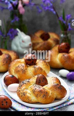 Easter buns, colored eggs and flowers on a gray concrete background. Stock Photo