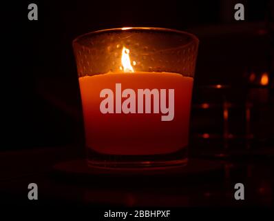 A candle was photographed in low light with candlelight illuminating the rest of subject. Giving the photograph a cozy home feel. Stock Photo