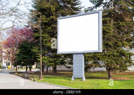 Blank billboard mockup with copy space in a pablic park on a spring day. Empty banner for advertisement. Large white screen for your text. Outdoors. Stock Photo