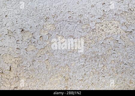 Texture of cracked gray paint on an old weathered wall. Dirty peeling paint on an outdoor surface. Grunge background. Front view. Stock Photo