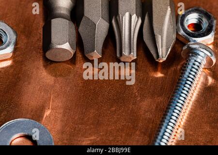 A macro image composed for Copy writing with 4 drill driver bits in star, phillips and square with the back of the 4th bit showing.  Several nuts, was Stock Photo