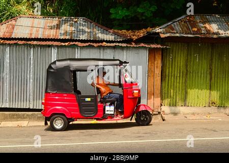 Kadugannawa, Sri Lanka - February, 2014: Tuk tuk driver waiting for passengers in his  three wheeler red auto rickshaw Stock Photo