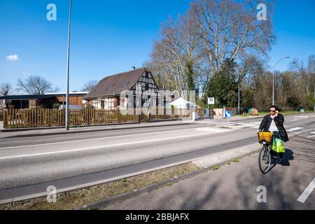 Strasbourg, France - Mar 18, 2020: Lonely woman on bike on empty usual busy intersection street now empty due to coronavirus outbreak Stock Photo
