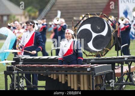 Asian American teenage girl plays the marimba in a high school marching band competition Stock Photo