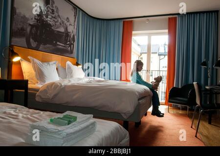 Girl sits on edge of bed and plays with stuffed bear in the contemporary hotel owned by singing group ABBA, Stockholm, Sweden, Europe Stock Photo