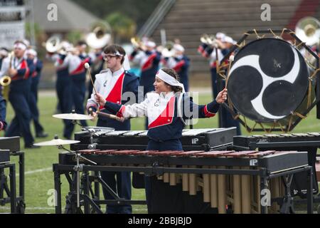 Asian American teenage girl plays the marimba in a high school marching band competition Stock Photo