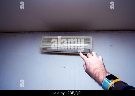 Male hand pointing to old rusty AC device on the wall of an old abandoned house Stock Photo