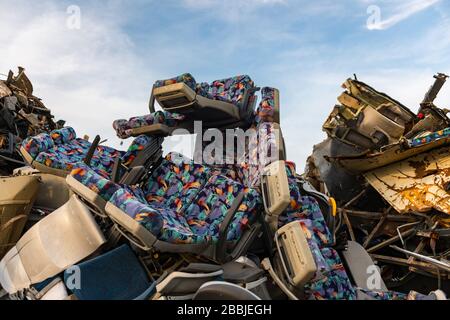 A pile of pairs of seats from a bus in a junkyard Stock Photo